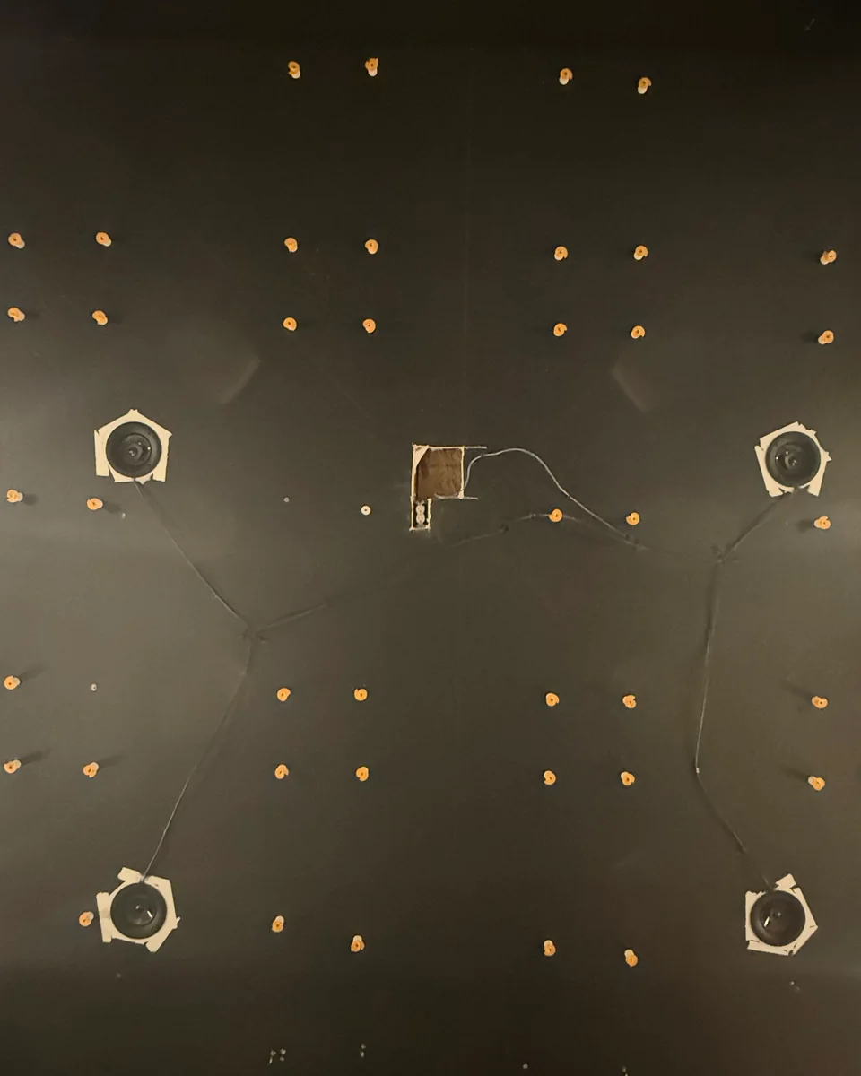 A prepared dark ceiling with a grid of mounting anchors, routed wiring and four taped-off fixtures, before the star field is installed