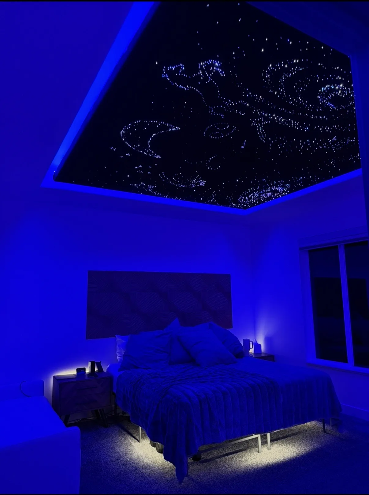 Bedroom starlight ceiling with constellation designs glowing above a bed